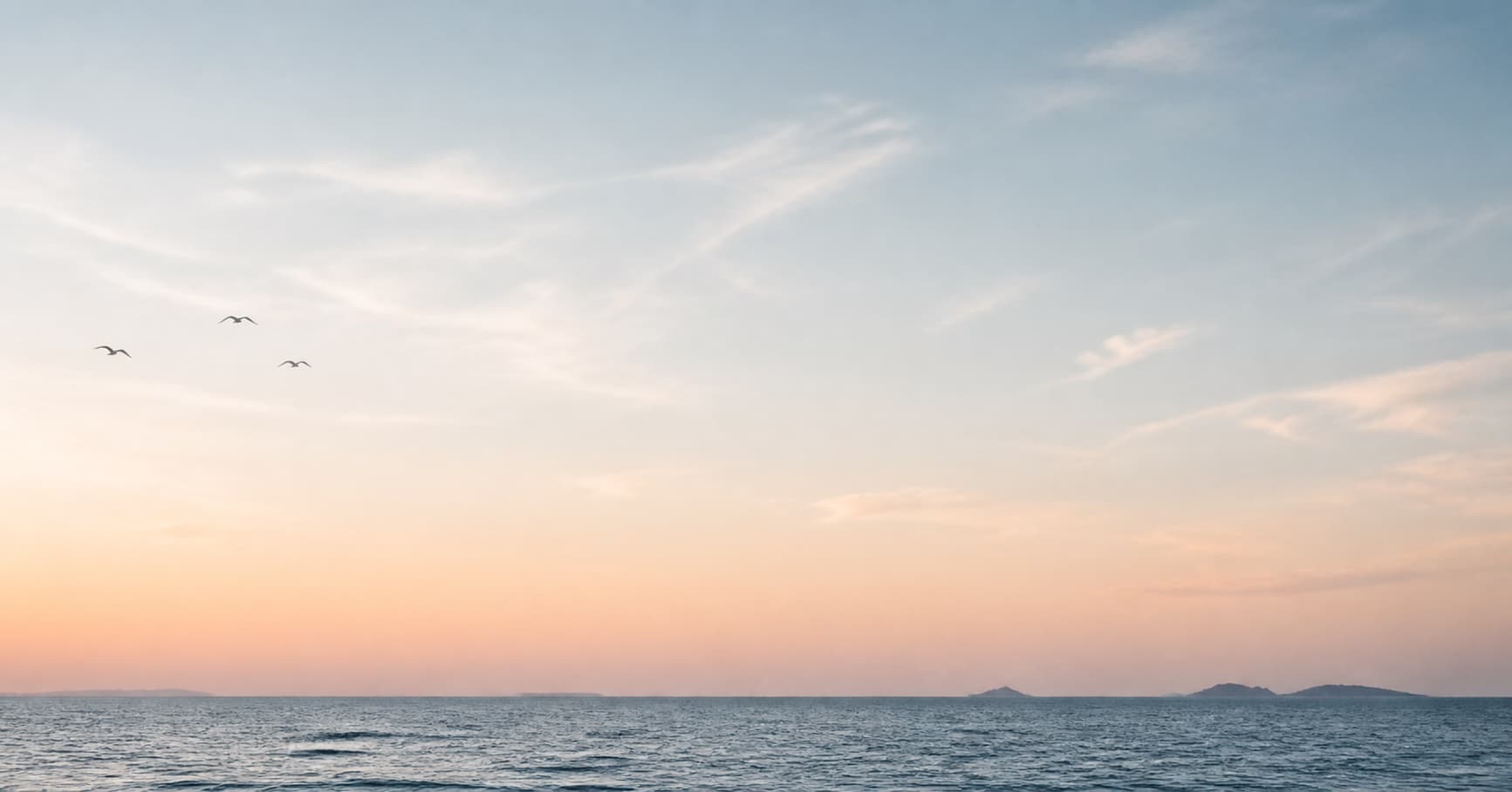 Calm ocean beneath a soft dawn sky